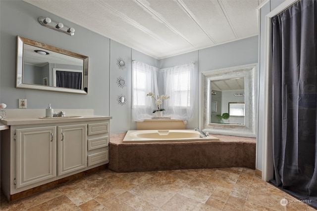 bathroom with vanity, a textured ceiling, and a tub