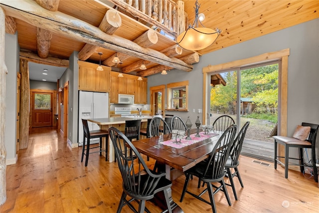 dining room with light wood-type flooring, beamed ceiling, and wooden ceiling