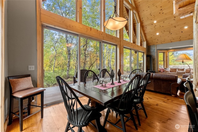 dining room with high vaulted ceiling and light hardwood / wood-style flooring