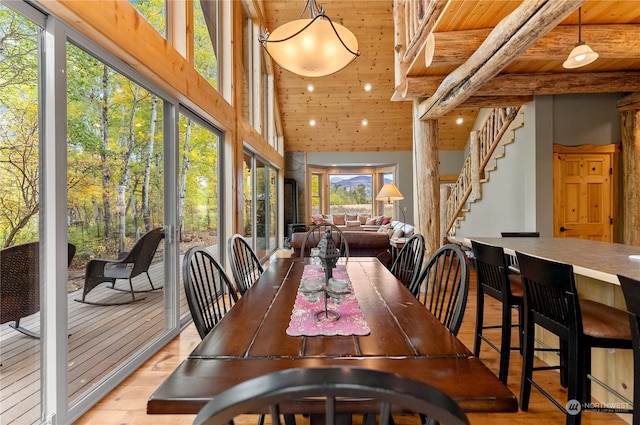 dining room with a high ceiling, wooden ceiling, and light hardwood / wood-style flooring