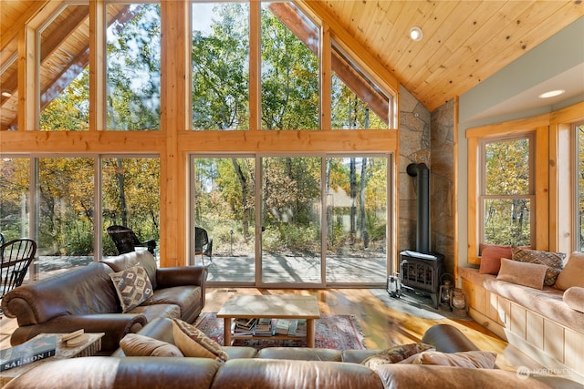 interior space with wood-type flooring, wooden ceiling, a wood stove, and high vaulted ceiling