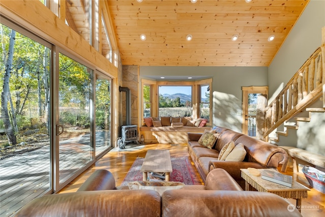 living room with a wood stove, a wealth of natural light, wooden ceiling, and light hardwood / wood-style flooring