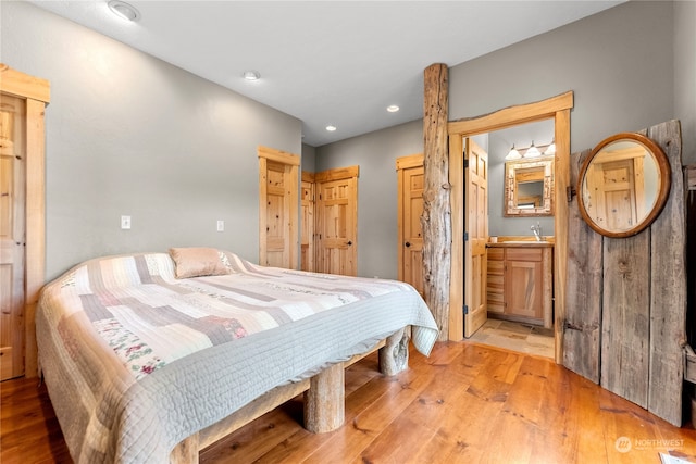 bedroom with light wood-type flooring and connected bathroom