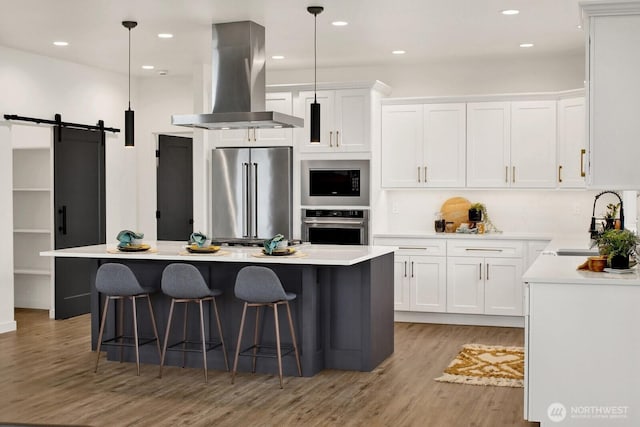 8721 Semiahmoo Dr, Blaine, WA 98230 - kitchen featuring island range hood, a sink, light wood-style floors, stainless steel appliances, and white cabinetry