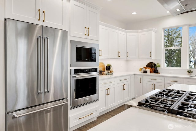 8721 Semiahmoo Dr, Blaine, WA 98230 - kitchen featuring appliances with stainless steel finishes, wood finished floors, light countertops, white cabinets, and recessed lighting