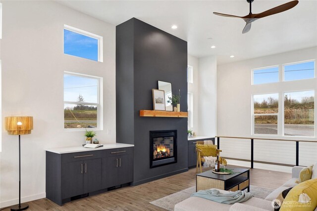 8721 Semiahmoo Dr, Blaine, WA 98230 - living room featuring light wood-style floors, a towering ceiling, ceiling fan, and a glass covered fireplace