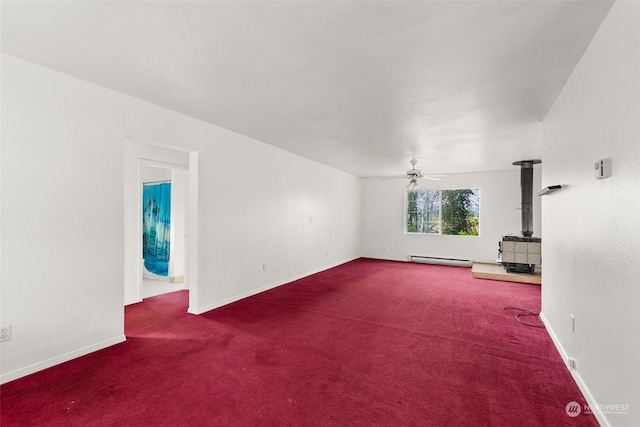 unfurnished living room featuring a wood stove, ceiling fan, a baseboard heating unit, and carpet