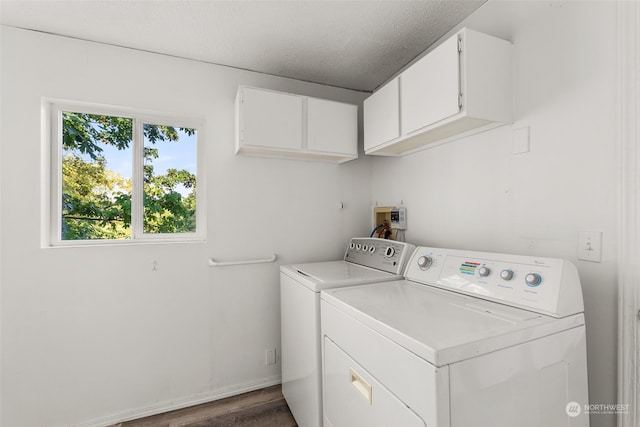 clothes washing area featuring washing machine and dryer, a textured ceiling, dark wood-type flooring, and cabinets