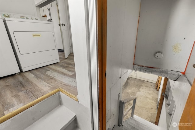 laundry room with water heater, light hardwood / wood-style flooring, and washer / dryer