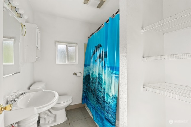 bathroom with a shower with curtain, tile patterned floors, and toilet