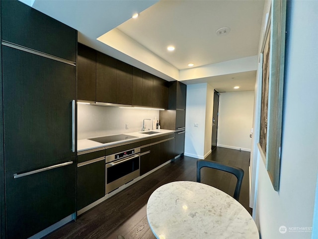 kitchen featuring sink, built in refrigerator, dark wood-type flooring, stainless steel oven, and black electric stovetop