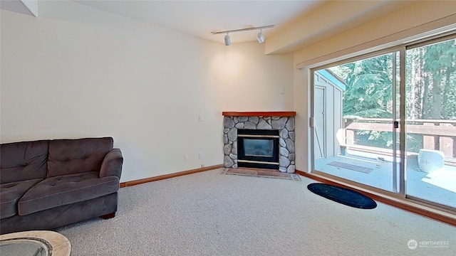 living room with a healthy amount of sunlight, a stone fireplace, rail lighting, and carpet flooring