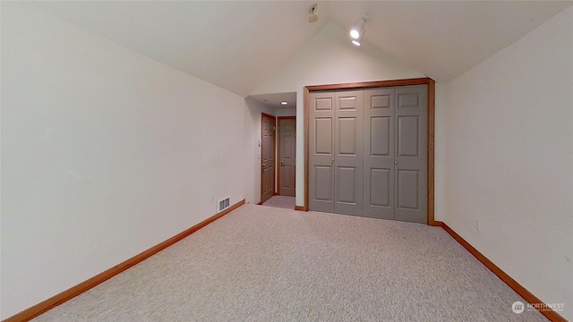 unfurnished bedroom with a closet, vaulted ceiling, and carpet