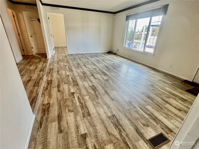 empty room featuring light hardwood / wood-style floors and ornamental molding