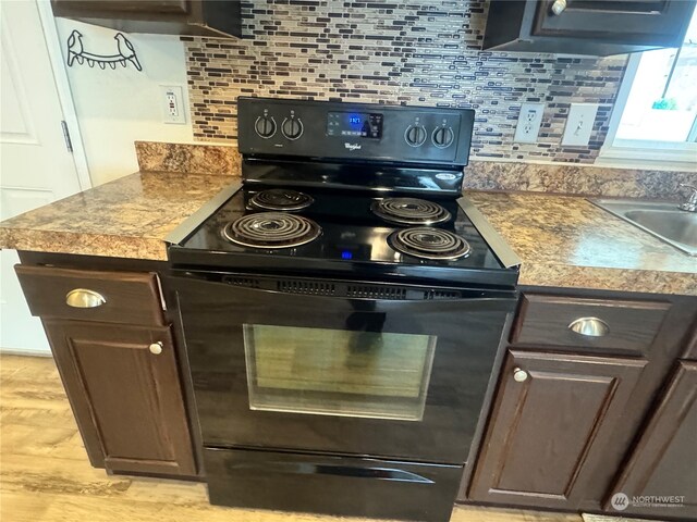 kitchen with dark brown cabinets, backsplash, black range with electric stovetop, and sink