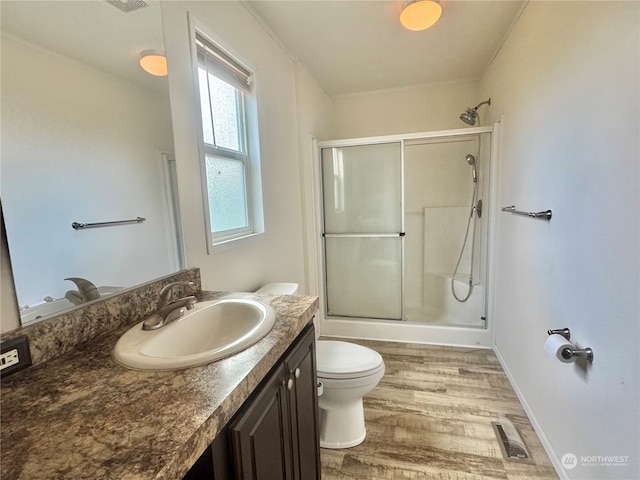 bathroom featuring wood-type flooring, vanity, toilet, and a shower with shower door