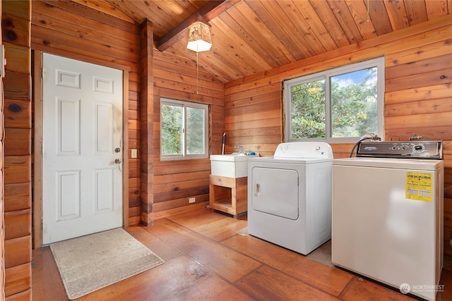 laundry area featuring wood walls, wood ceiling, plenty of natural light, and washer and dryer