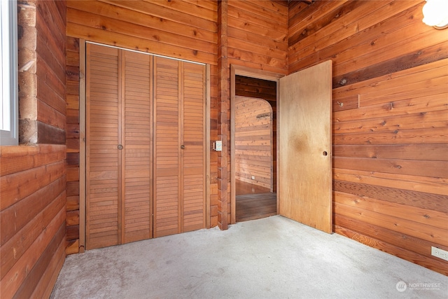 unfurnished bedroom featuring wood walls, a closet, and carpet