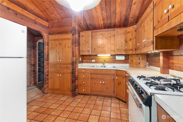 kitchen with white appliances, sink, wooden ceiling, light hardwood / wood-style floors, and wood walls