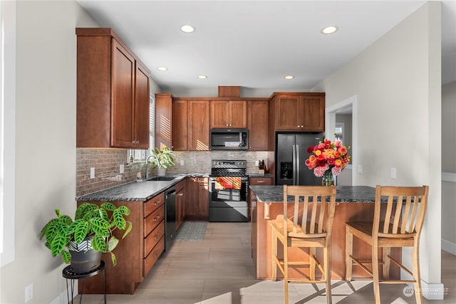 kitchen featuring sink, a breakfast bar area, dark stone countertops, tasteful backsplash, and stainless steel appliances