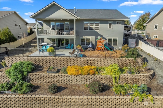 back of house with a patio area, a balcony, and a playground