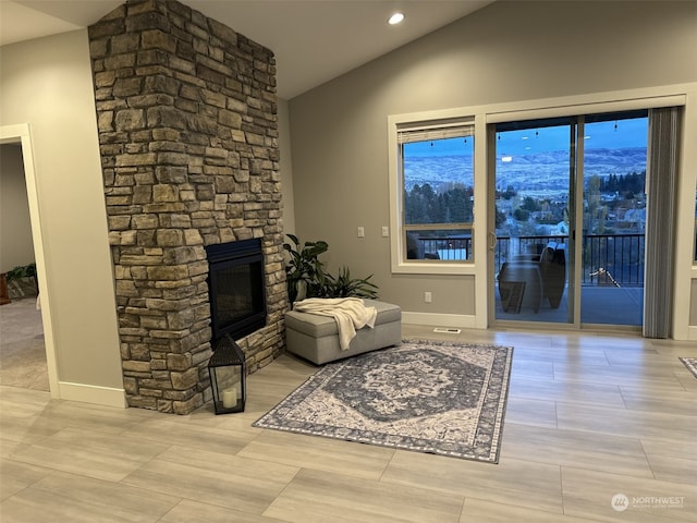 living room featuring a stone fireplace, a mountain view, and vaulted ceiling