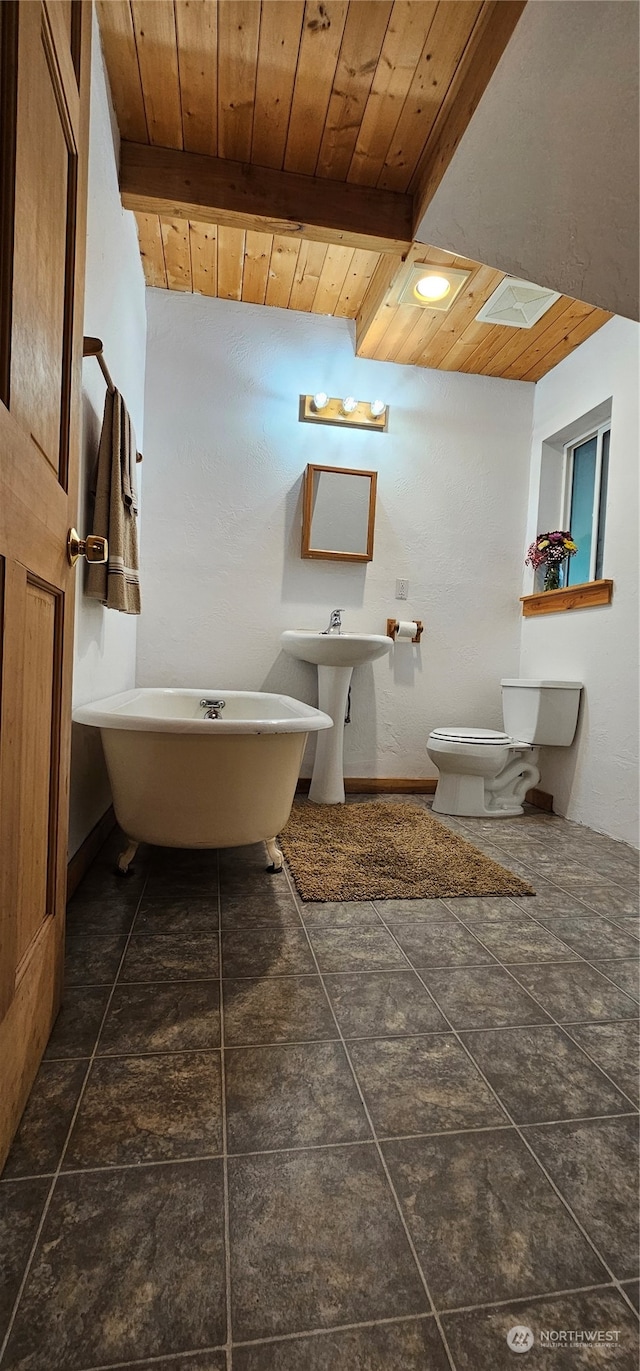 bathroom featuring a washtub, wooden ceiling, tile patterned floors, beam ceiling, and toilet