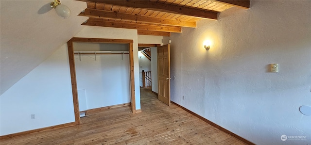 unfurnished bedroom with vaulted ceiling with beams, a closet, wood ceiling, and hardwood / wood-style floors