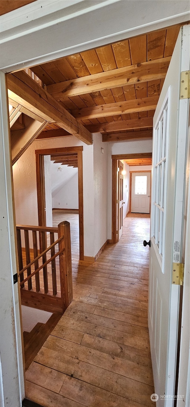 hallway with light hardwood / wood-style flooring, beam ceiling, and wooden ceiling