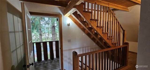 stairway with wood ceiling, beamed ceiling, and hardwood / wood-style flooring