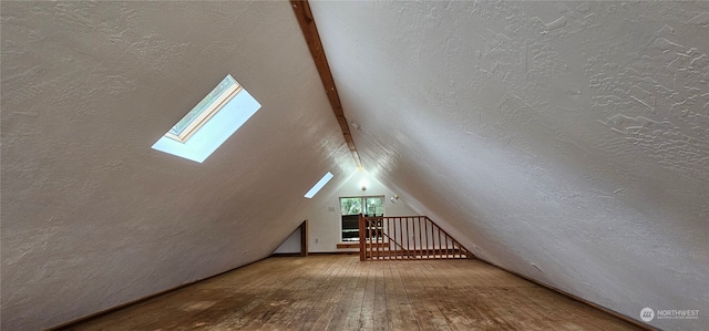 bonus room featuring a textured ceiling, wood-type flooring, and vaulted ceiling with skylight