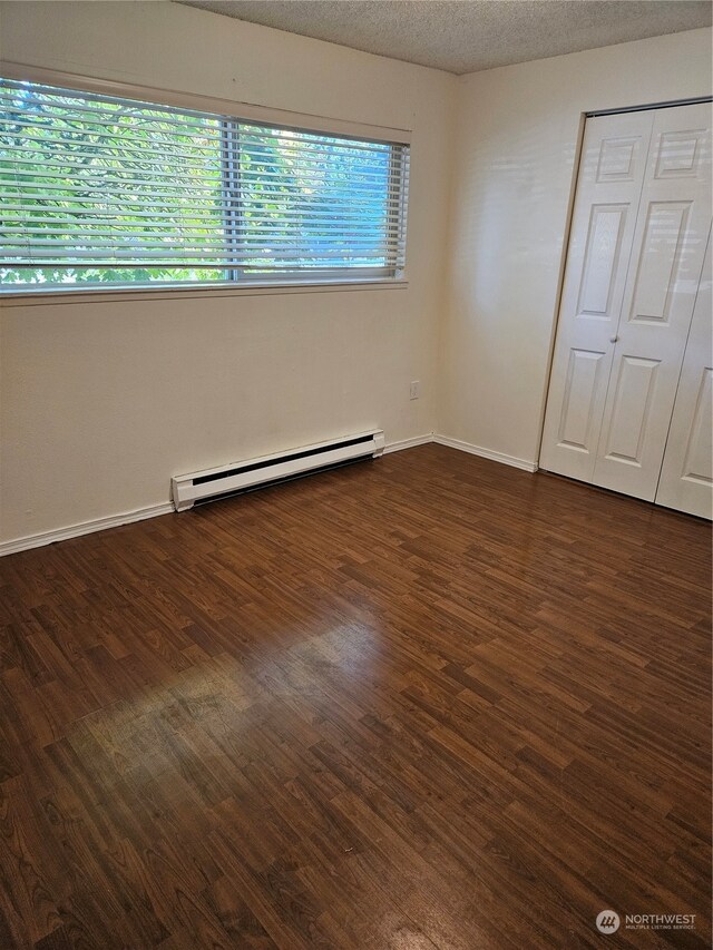 31003 14th Ave S Unit E-10, Federal Way, WA 98003 - unfurnished bedroom featuring dark hardwood / wood-style flooring, a baseboard radiator, a closet, and a textured ceiling