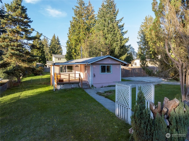 rear view of property with a deck, a patio, and a lawn