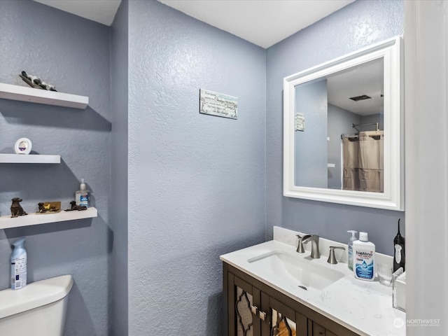 bathroom with walk in shower, vanity, and toilet