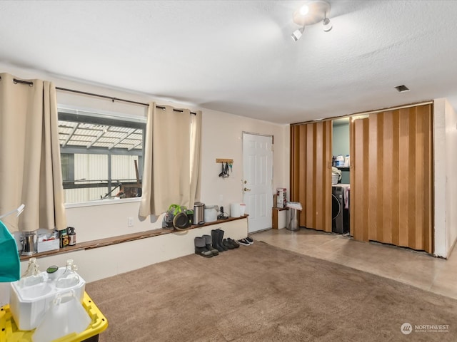 misc room with light carpet, a textured ceiling, and washer / dryer