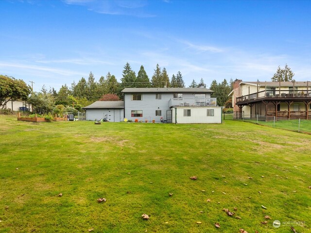 rear view of property featuring a wooden deck and a lawn