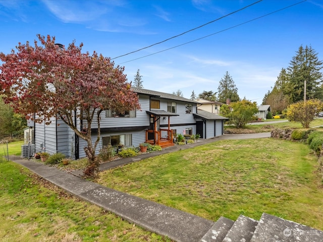 view of front of property with central AC unit, a front yard, and a garage