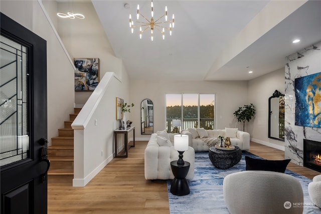 living room with a notable chandelier, light hardwood / wood-style floors, and a premium fireplace