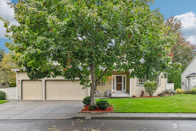 view of property hidden behind natural elements featuring a front yard and a garage