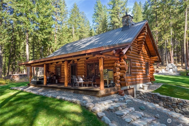 back of house with a chimney, a yard, log exterior, and metal roof