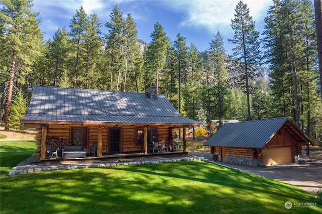 cabin featuring a porch, log exterior, a front yard, and a detached garage