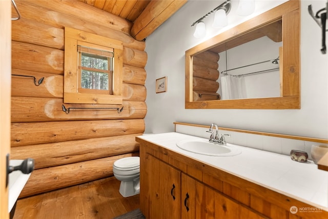 bathroom with hardwood / wood-style floors, log walls, vanity, wooden ceiling, and toilet