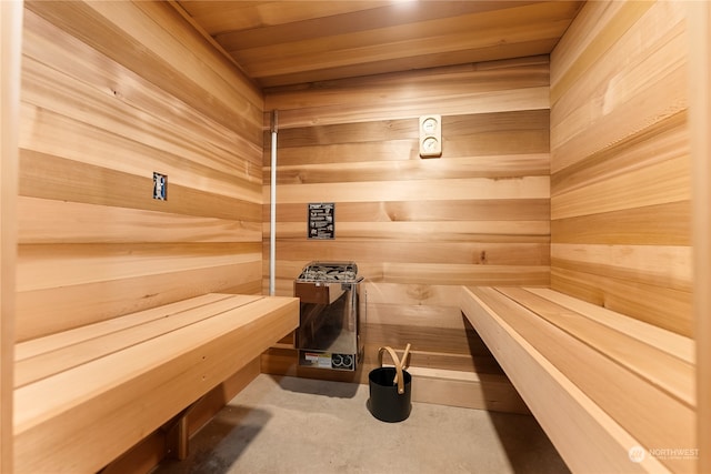 view of sauna / steam room featuring wood walls, wooden ceiling, and concrete flooring