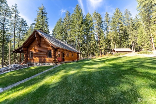 view of side of property featuring a lawn, log siding, metal roof, and a wooded view