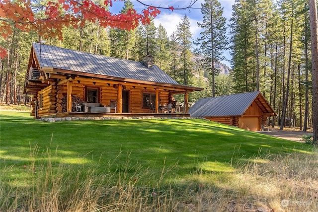 back of property featuring an outdoor structure, a chimney, log exterior, metal roof, and a yard