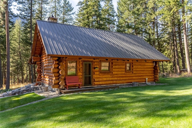 view of front of home with a chimney, a front yard, log exterior, and metal roof