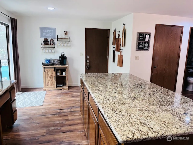 kitchen with wood-type flooring, a kitchen island, and a healthy amount of sunlight