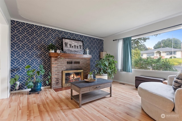 living room featuring ornamental molding, a brick fireplace, and light hardwood / wood-style floors