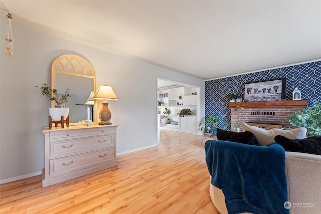 living room featuring a brick fireplace, light hardwood / wood-style flooring, and built in features