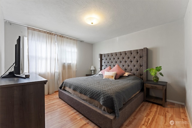 bedroom with a textured ceiling and light wood-type flooring